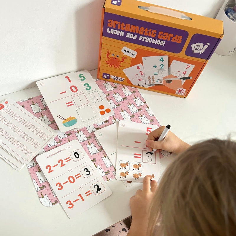 Dziecko rozwiązuje zadania matematyczne na kartach WOOPIE